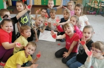 Zadowolone dzieci z przedszkola z wyciętymi serduszkami na dłoniach 