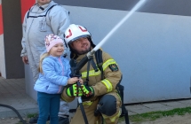Dziewczynka leje wode wezem gasniczym.