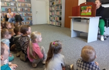 Pani bibliotekarka przezentuje dzieciom bajke w teatrzyku kamishibai.