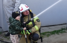Chlopiec i strazak leja wode z weza strazackiego