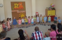 Dzieci z gr. I stoja w polkolu na tle napisu Jedziemy na wakacje