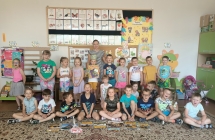 Dzieci z gr. VII w sali przedszkolnej z mama Wojtka pozuja przed tablica