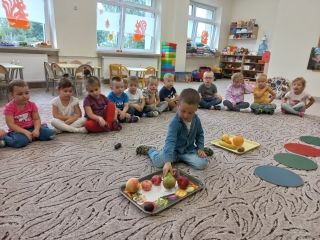 Dzieci z gr. III obserwuja kolege segregujacego owoce.