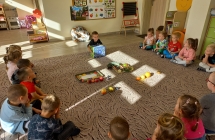 Czterolatki  na dywanie podczas zabawy z magicznym pudelkiem i owocami.
