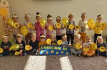 Usmiechniete dzieci z emotkami i zoltymi balonami