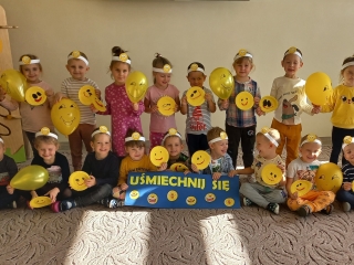 Usmiechniete dzieci z emotkami i zoltymi balonami