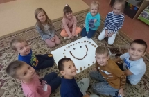 dzieci ukladaja emotikonki z materialu przyrodniczego