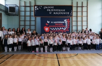 Spolecznosc przedszkolna w sali gimnastyczne j przed odspiewaniem hymnu.