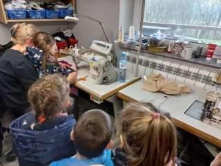 Dziewczynka szyje z pania krawcowa na maszynie.