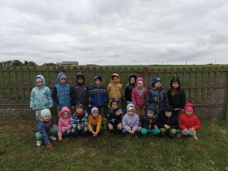 Przedszkoalki z grupy Kotki przy posadzonym drzewie na placu przedszkolnym