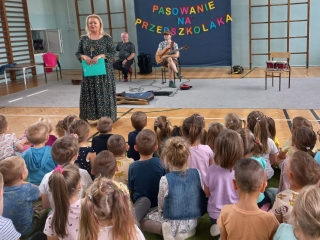 Dzieci sluchaja zapowiedzi prowadzacej audycje.