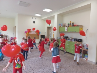 Czterolatki odbijaja czerwone balony w ksztalcie serca.