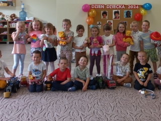 Dzieci z gr. III  w sali z ulubionymi zabawkami na tle napisu Dzien Dziecka 2024