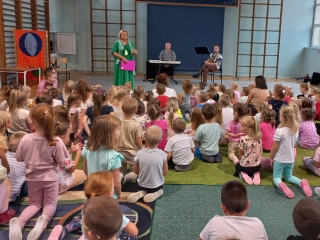 Prowadzaca audycje i muzycy witaja przedszkolakow.