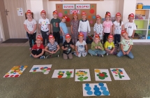 Usmiechniete dzieci w kolorowych opaskach przed swoimi pracami.