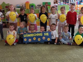 Radosne pieciolatki z gr. VI z zoltymi balonami i napisem - usmiechnij sie