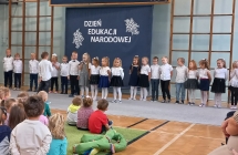 Wystepujace szesciolatki na tle napisu Dzien Edukacji Narodowej.