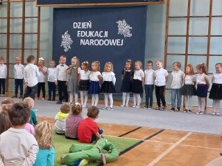 Wystepujace szesciolatki na tle napisu Dzien Edukacji Narodowej.