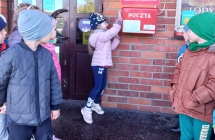 Dzieci z gr. VI obserwuja jak kolezanka wrzuca list do skrzynki pocztowej.