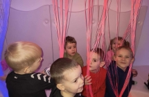 dzieci chowaja sie za kolorowa swiecaca zaslona