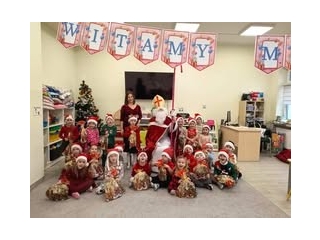 dzieci z grupy IV siedza wokol Mikolaja z prezentami