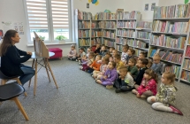 Dzieci z grupy VI sluchaja bajki prezentowanej przez pania bibliotekarke w teatrzyku kamishibai.