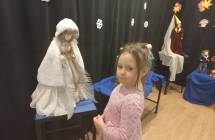 Dziewczynka oglada lalke z muzealnej wystawy.