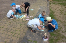 Chlopcy z gr. VI rysuja kreda na chodniku.