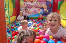 Dzieci bawia sie w dmuchancu z kolorowymi kulkami.