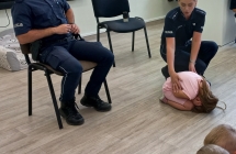 Dziewczynka pod kierunkiem policjantow demonstruje pozycje zolwia.