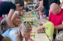 Dzieci z rodzicami wykonuja prace plastyczna- wianek dla Pani Lato. Wyklejaja kwiaty.