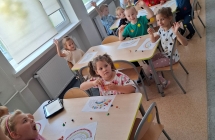 Dzieci z grupy siodmej wykonuja prace plastyczna wykorzystujac plasteline. Radosnie machaja.