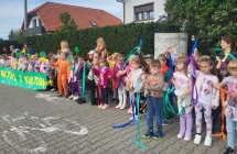 Przedszkolaki wymachuja  kolorowymi wstazkami i kwiatami.