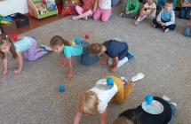 Dzieci chodza na czworakach, majac na plecach talerzyki z pileczkami