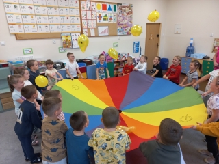 Radosne dzieci z gr. IX podczas zabawy z chusta animacyjna.