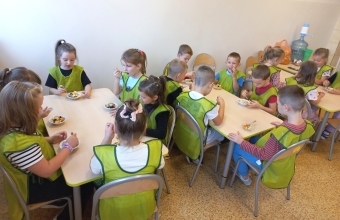 Dzieci w przedszkolnej stolowce podczas przygotowywania salatki.