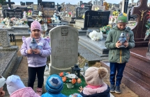 Przedszkolaki ze zniczami przy grobie dzieci.