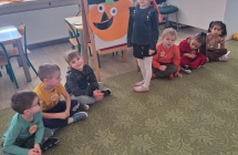 Dzieci przyczepiaja oczy, nos i usta dyni z zamknietymi oczami.