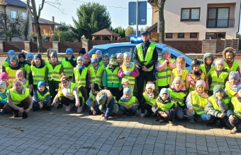 Zdjecie grupwe dzieci i policjanta na tle radiowozu.