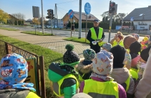 Policjant na chodniku tlumaczy dzieciom zasady ruchu drogowego.