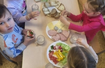 Dziewczynki i chlopiec samodzielnie komponuja kanapki uzywajac zdrowych produktow przyniesionych z domow.