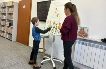 Chlopiec w bibliotece przypina  na tablicy element piramidy zdrowia.