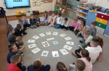 Szesciolatki z gr. IX w kregu z ulozonymi na dywanie obrazkami ilustrujacymi prawa dziecka.