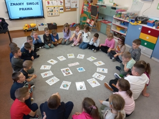 Szesciolatki z gr. IX w kregu z ulozonymi na dywanie obrazkami ilustrujacymi prawa dziecka.