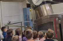 Dzieci  z grupy VII ogladaja proces przekladania gotowego ciasta chlebowego do krajalnicy.