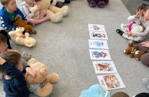 Dzieci z grupy siodmej siedza na dywanie, rozmawiaja i poznaja slawne Misie.