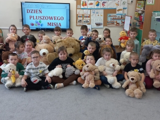 Dzieci z gr. IX ze swoimi misiami na tle napisu Dzien Pluszowego Misia.