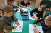 Dzieci z gr. IX przy stoliku wykonuja zadania na kartach pracy.