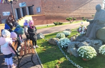 Dzieci 5 letnie wraz z Pania poznaja Dzien Wszystkich Swietych zapalajac znicz pod pomnikiem Papieza w Malanowie.