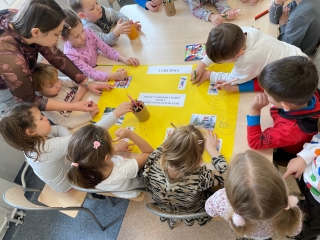 Dzieci wspolnie ozdabiaja plakat.